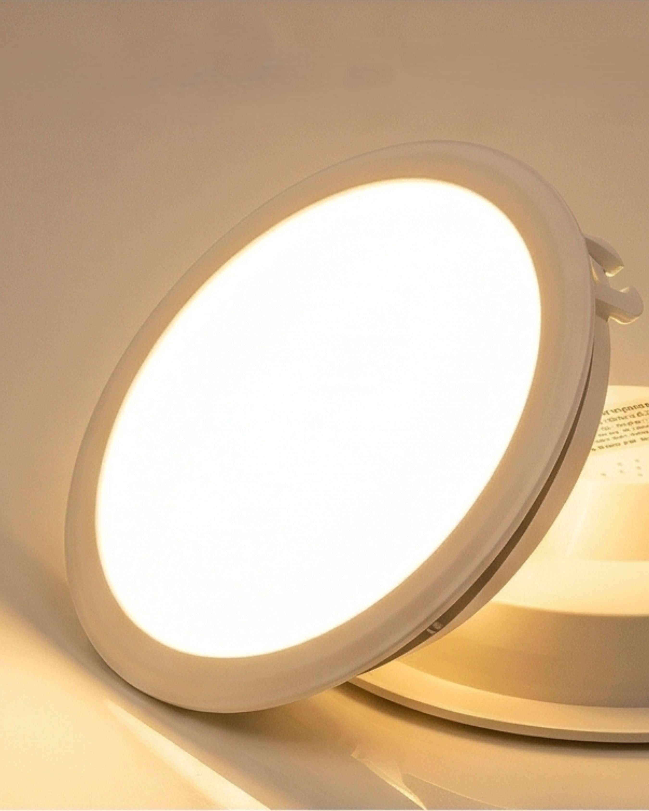 Round LED light fixture emitting a warm glow on a beige background